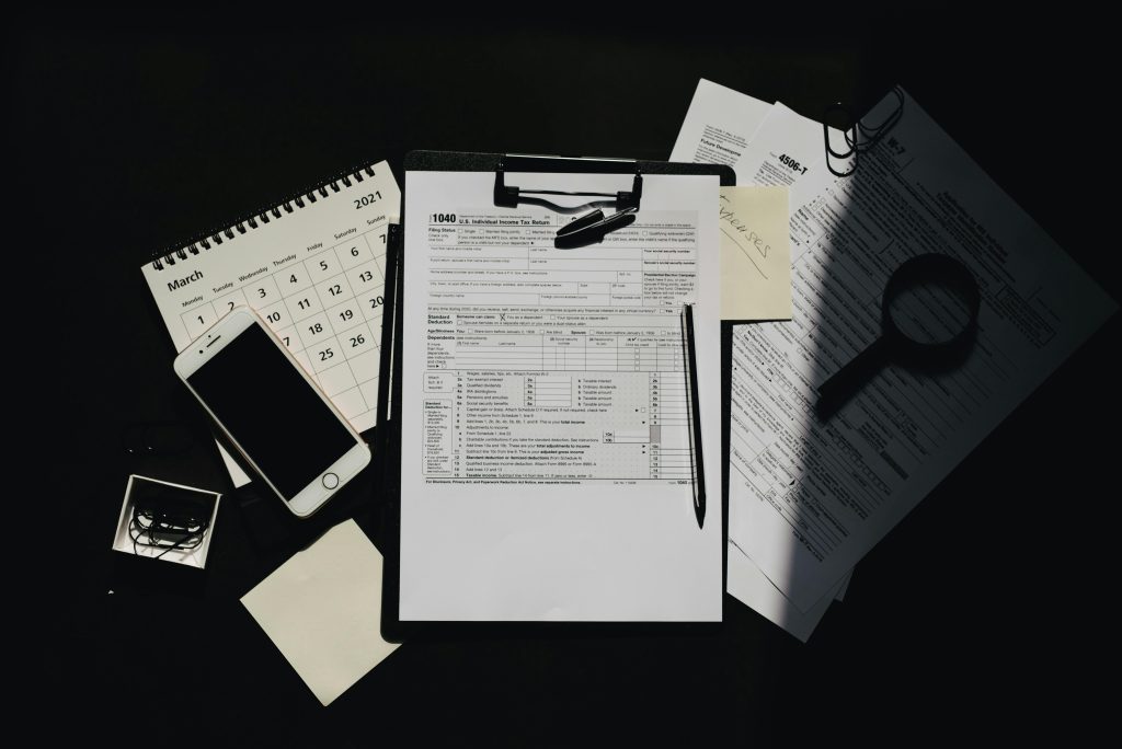 Flat lay of tax documents, calendar, and smartphone on a dark surface, symbolizing tax preparation.